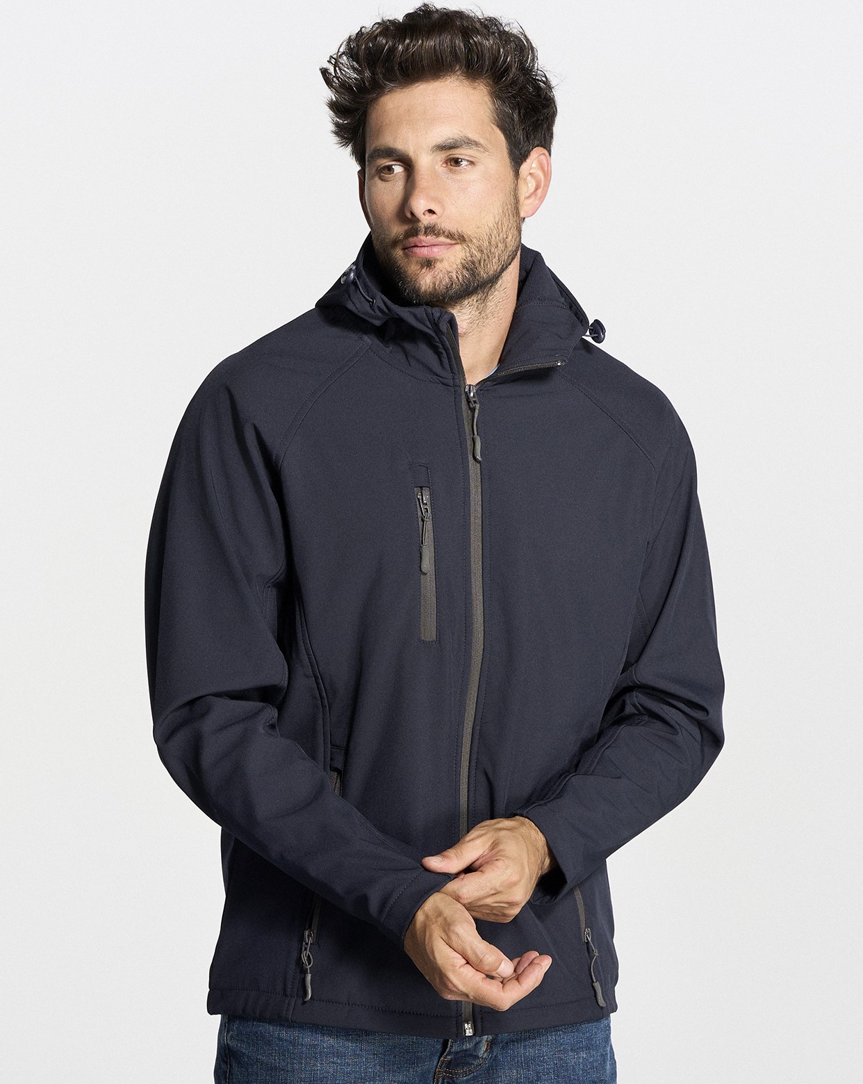 Mężczyzna w kurtce softshell z kapturem JHK HOOD JACKET granatowy.Kurtka zapinana na zamek.Ma trzy zewnętrzne kieszeńie zapinane na zamek.Wnętrze wykończone polarem.Stopery.Skład:94% Poliester z recyklingu 6%Elastan.Gramatura 300g.Wodoodporna_dostępna na koszulkisuper.com